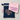 A folded light pink T-shirt with purple text reading 'I've got a secret' is placed on top of a navy blue zip pouch with a pink carabiner and a peach 'Baby' print. The items are arranged on a light gray background.