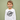 A young boy wearing a white long-sleeve t-shirt with a black circular graphic that reads 'Best Brother Ever', set against a solid sage green background.