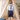 Child wearing a light blue shirt with suspenders and dark shorts in a softly lit room.