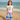 Young girl in mermaid-themed outfit standing on a beach with ocean in the background