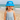 Happy young girl, about four years old, wearing a personalised blue bucket hat with ladybug design that sits naturally on her head, paired with a pale blue linen sundress, at the beach.”