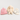 A baby gift set featuring a pink knit beanie, a cream plush bunny toy, and cream baby socks with gray 'Lamin' text and cross patterns, arranged on a light gray background.