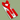 A red fabric bow tie and matching suspenders set with silver metal clips, displayed on a white backing card against a muted sage green background.