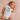 Newborn baby wearing a white onesie with 'new to the crew' text on a soft pink blanket.