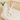 White plush bunny toy on a crib with a patterned blanket and plant 