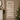 A vertical fabric Christmas countdown calendar hanging on a wall in a decorated living room, with a lit Christmas tree and fireplace visible around it.