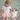 Two children, one wearing a 'BIG sister' shirt and the other in a 'LIL sister' onesie, on a green blanket.